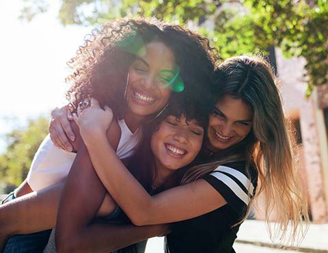 Three friends hugging outdoors.